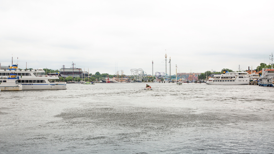 Nybroviken med båtar på båda sidor. Vasamuseet  och berg- och dalbana i  bakgrunden, foto.